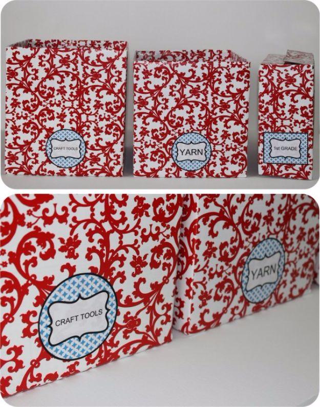 Cardboard craft storage boxes covered in red and white damask paper with oval labels reading craft tools and yarn