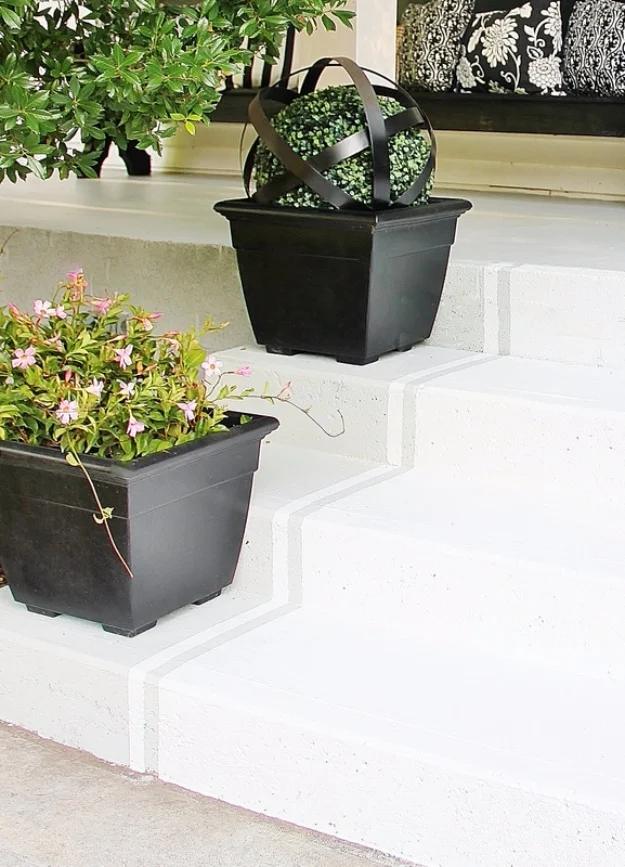 DIY curb appeal porch steps painted crisp white with two black square planters of flowers staged on the treads