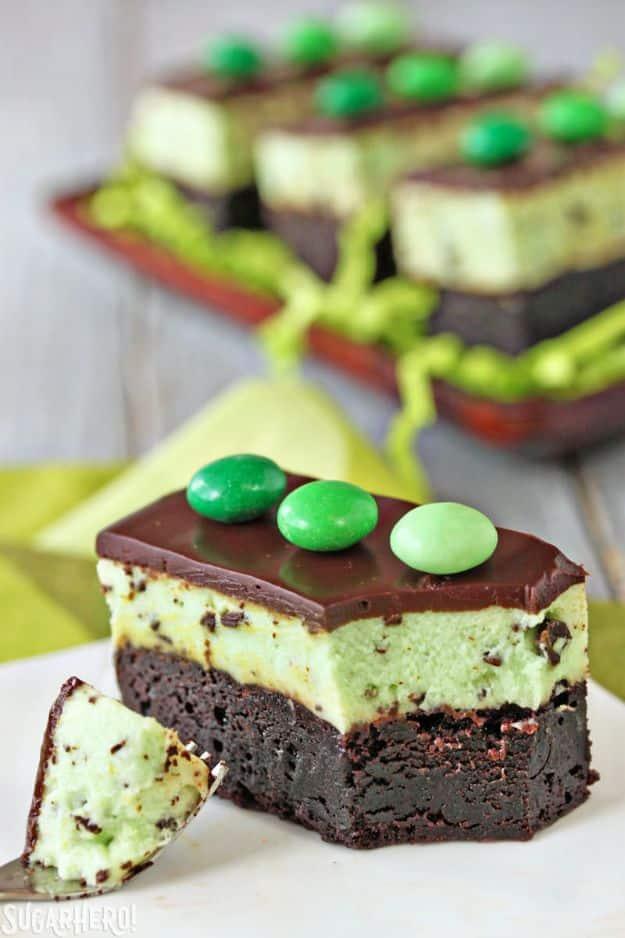 Mint chocolate chip mousse brownies with a pale green mousse layer, dark glaze and green candies on top