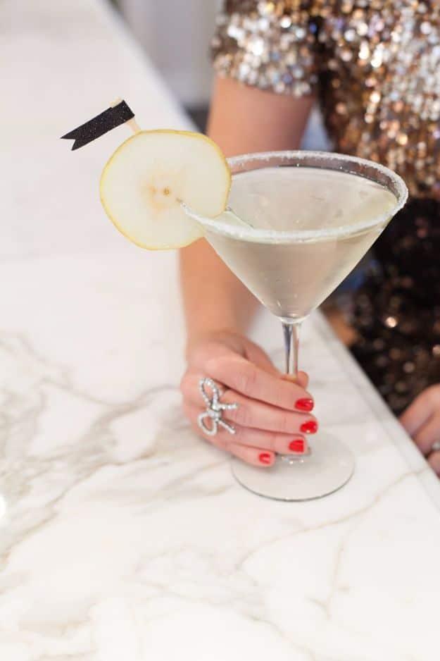 A hand holding a French pear martini in a sugar rimmed glass garnished with a thin slice of fresh pear