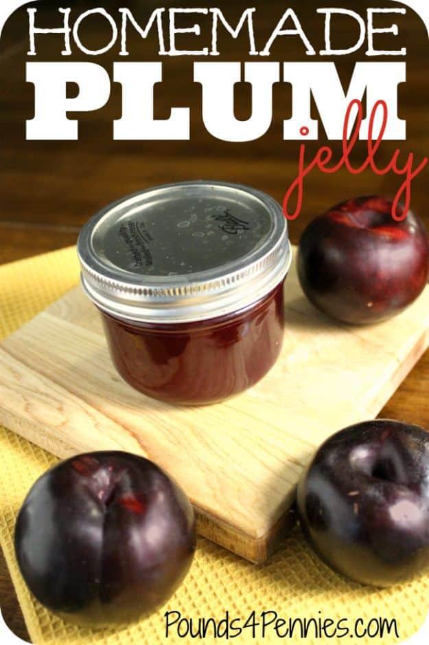 Homemade plum jelly in eight canning jars, deep ruby and clear, cooling on a kitchen towel after processing