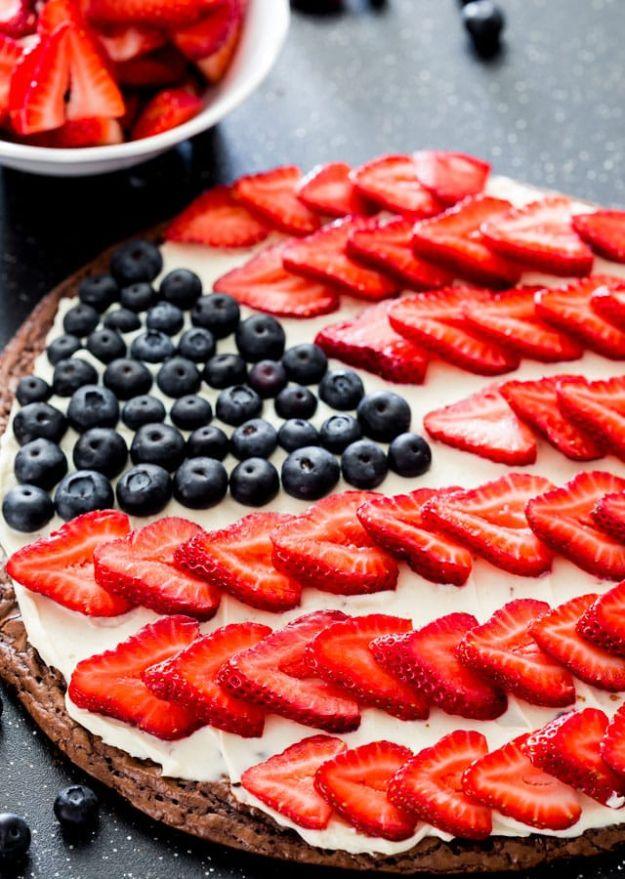 Red white and blue brownie pizza topped with cream cheese icing, sliced strawberries and blueberries as a flag