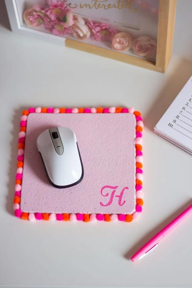 Pom pom mouse pad, a pink monogrammed cork square edged in bright pink pom poms with a white mouse on top