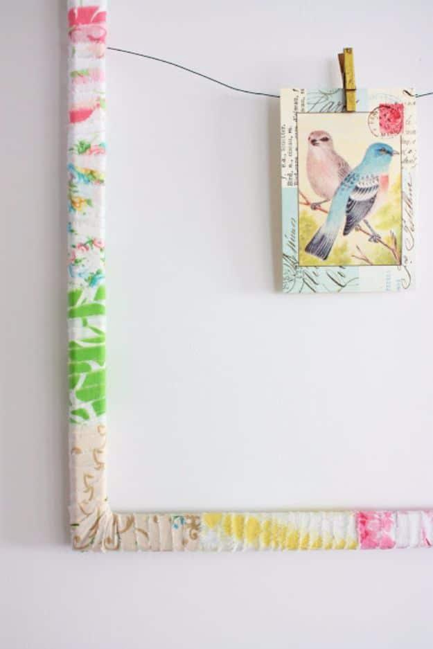 Quilting scraps frame wrapped in strips of pink green and yellow vintage sheeting with a bird postcard pegged to wire