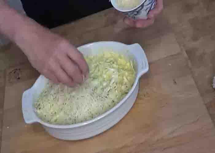 Adding shredded cheese on top of the cabbage casserole