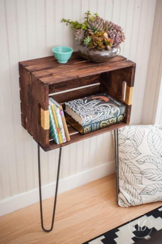 Wooden crate side table on black hairpin legs mounted on a wall holding books with a teal bowl on top