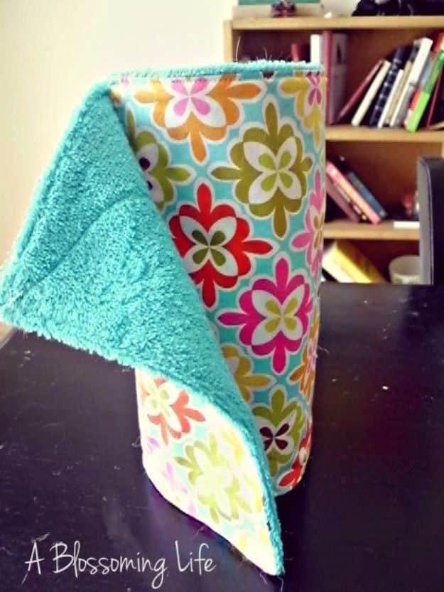 DIY unpaper towels made from teal terry cloth and bright floral cotton, draped over a black paper towel holder