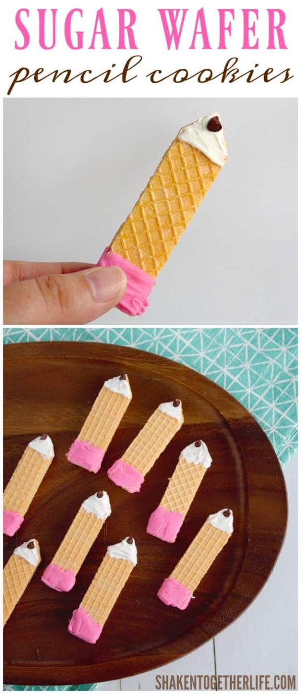 Sugar wafer pencil cookies dipped in pink and white chocolate with chocolate chip tips on a dark wood tray