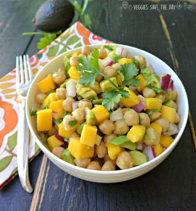 Tropical chickpea salad with diced mango, avocado and red onion tossed with cilantro in a white bowl