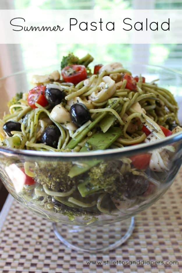 Summer pasta salad with spinach fettuccine, tortellini, cherry tomatoes and black olives in a footed glass bowl