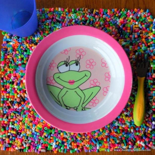 Perler bead placemats, a dense multicolored fused bead placemat under a frog patterned bowl and a green fork