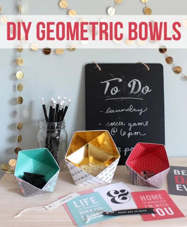 Typeset DIY Geometric Bowls title over three folded paper bowls in teal, gold and red on a desk with pencils