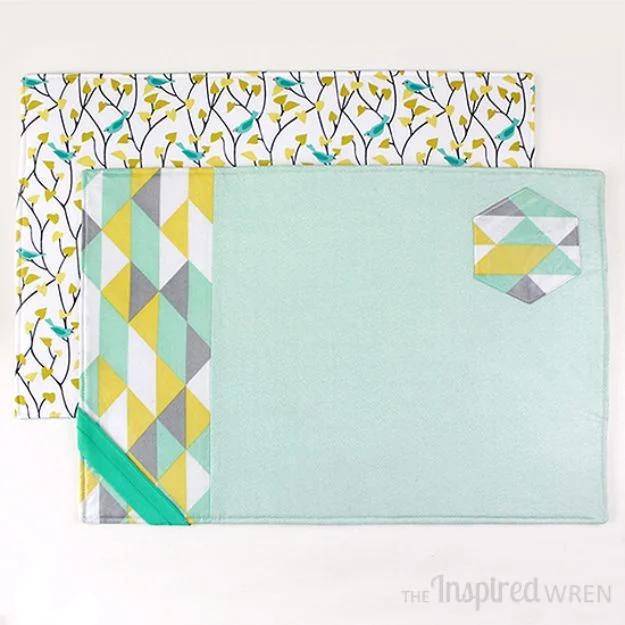 A quilted placemat in blue and white cotton with a built-in cutlery pocket, set on a wooden dining table.
