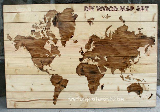 Wide wooden wall map of the world with continents stained dark brown against pale pine boards left bare for oceans