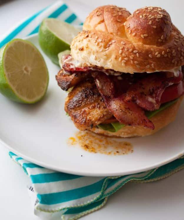 Lighter cajun tilapia sandwich with bacon, lettuce, tomato and lime mayo on a bun, an easy fish sandwich recipe