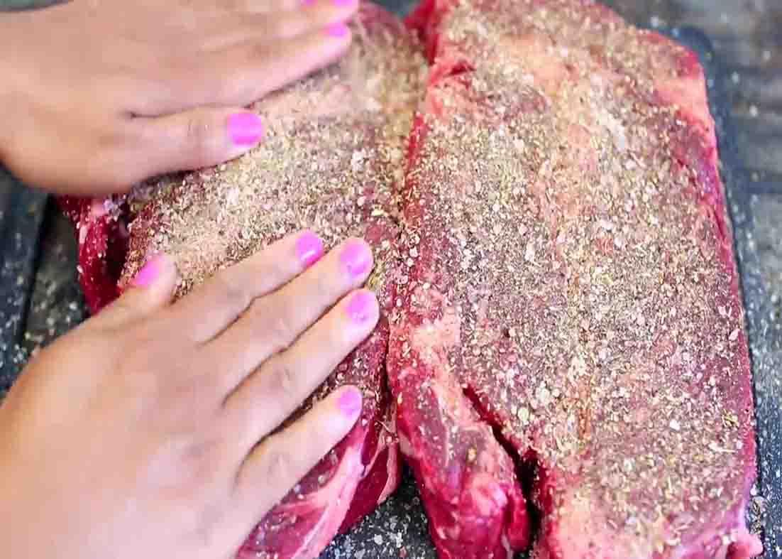 Rubbing both sides of the pot roast with spices
