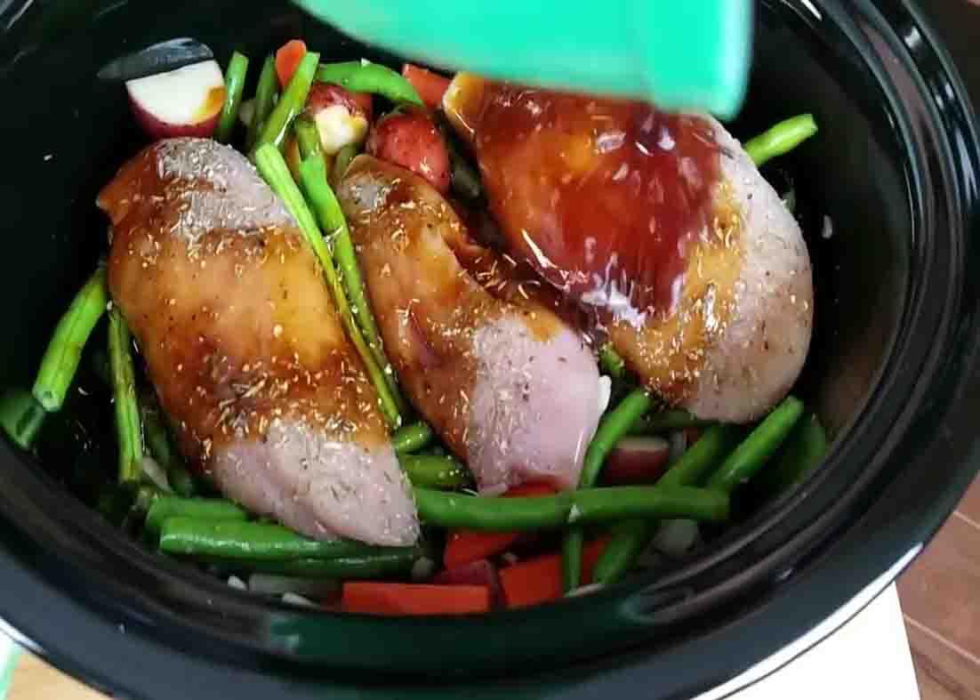 Pouring the sauce over the top of the chicken and veggies