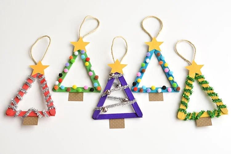 Five popsicle stick tree ornaments painted in bright colors with pom poms, tinsel, jingle bells, gold stars and twine loops