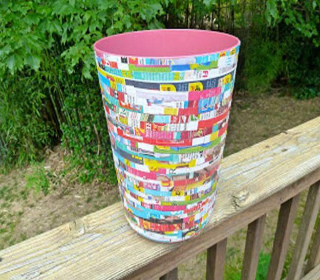 White trash can covered in hundreds of narrow multicolored paper strips, balanced on a wooden deck rail outdoors