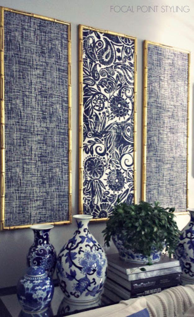 Three tall gilded frames holding indigo blue and white patterned fabric panels above a row of blue and white vases