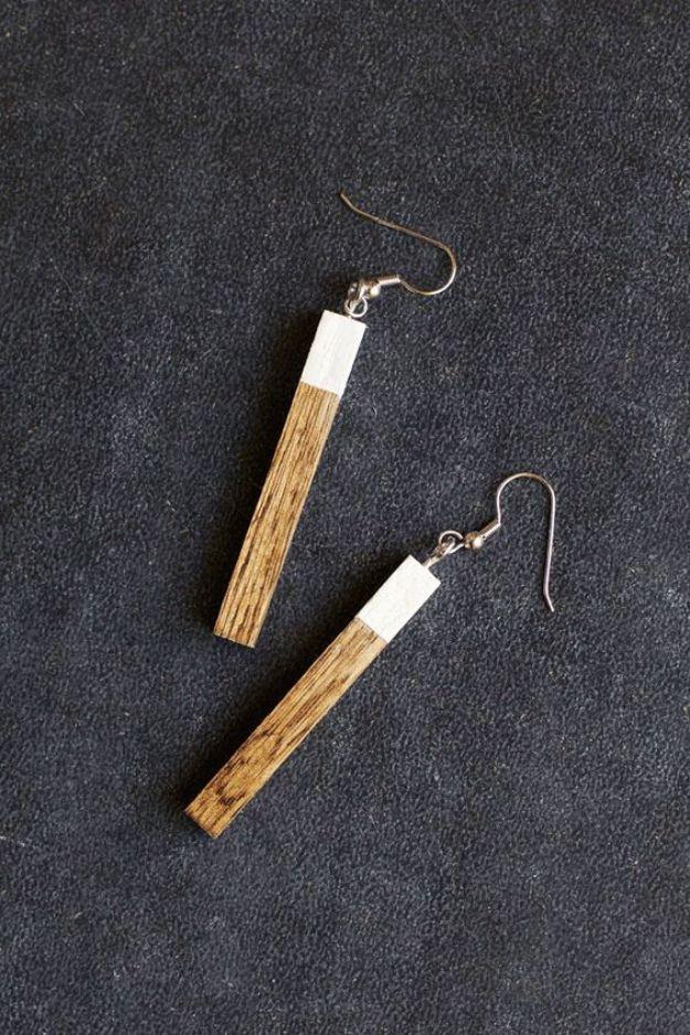 Modern wooden earrings, two slim wood bar dangles with white painted tips on silver ear wires, on dark gray felt