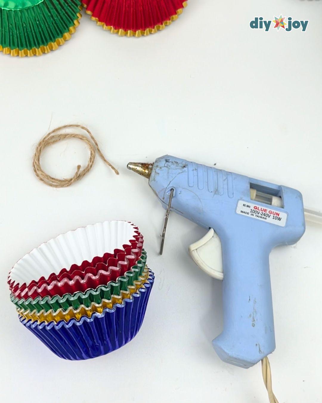 DIY Ideas - craft supplies flat lay with a blue hot glue gun, a coil of jute twine, and a stack of metallic cupcake liners