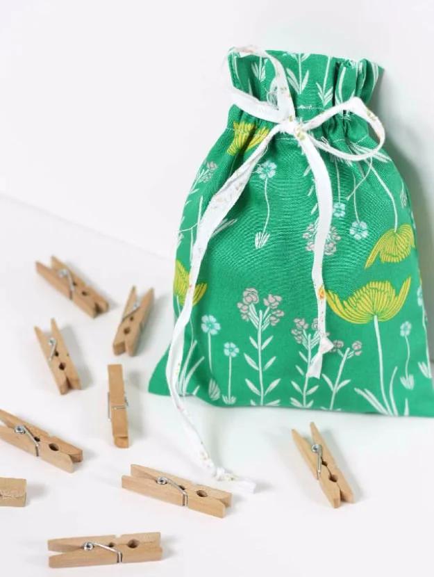 A cotton drawstring bag in soft blue print, cord pulled tight at the top, one of three sizes lined up for a craft fair