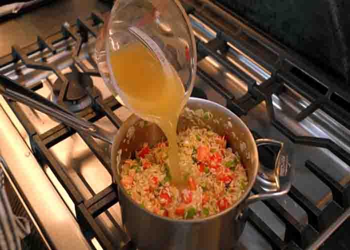 Adding the broth to the Mexican rice