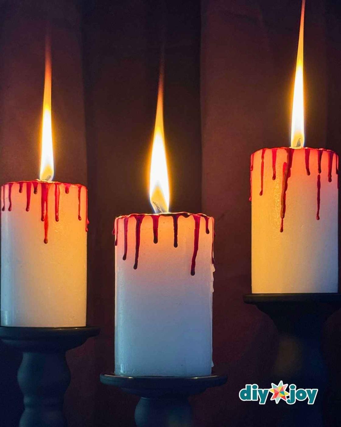 Spooky bloody candles grouped together as easy Halloween decor with dripping red crayon wax, just a candle and a few crayons.