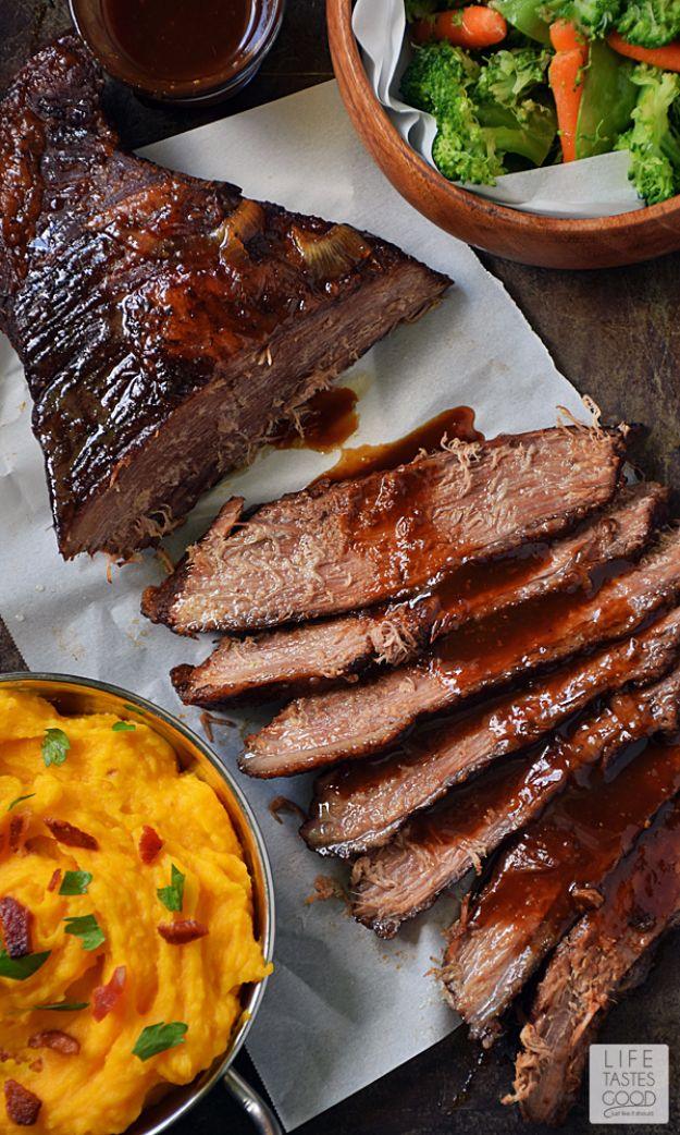 Beer braised beef brisket sliced on parchment with barbecue sauce and a bowl of macaroni and cheese.