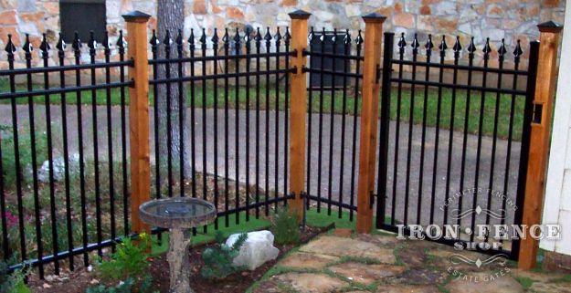 Iron fence, a black ornamental iron fence with spear tops set between stained cedar posts in front of a stone wall