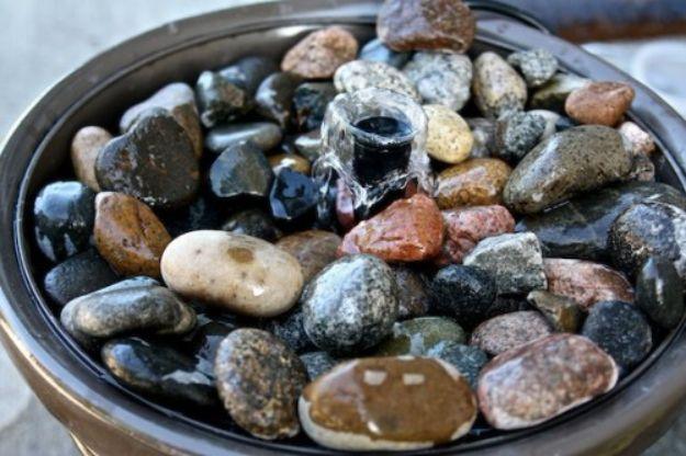 Close view of wet river rocks filling a dark bowl with a small bubbler pushing up through the center