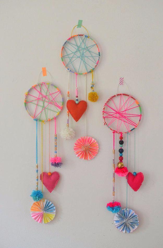 Three dream catchers on embroidery hoops wrapped in neon yarn, hung with felt hearts, pom poms, beads and paper fans