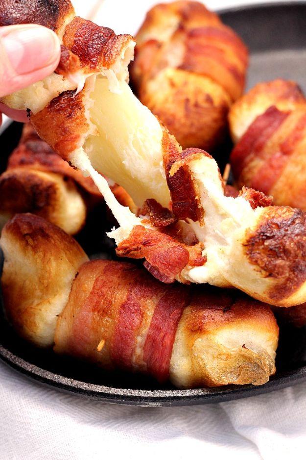 Bacon wrapped cheese bombs in a pan, biscuit dough parcels pulling apart to show stretching mozzarella