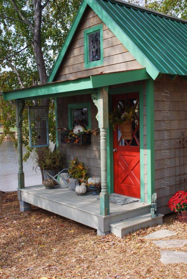 Potting shed, a cedar shingled shed with a green metal roof, red door, covered porch and pumpkins on the step