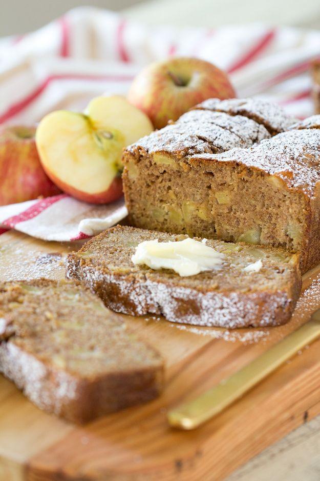 Cinnamon spice apple bread sliced and dusted with sugar, butter spread on one slice, apples and a knife nearby