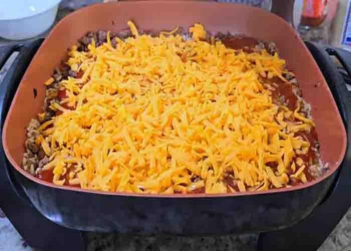Adding cheese to the beef and rice enchilada