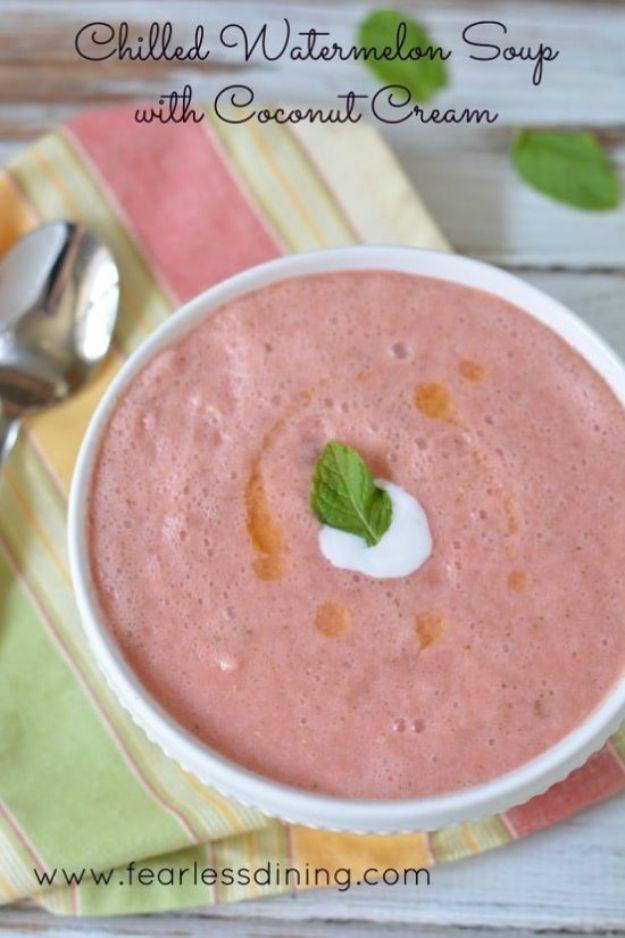 Chilled watermelon soup with coconut cream swirled in a white bowl and topped with a fresh mint leaf