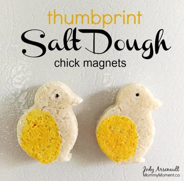 A salt dough disc with a child's thumbprint painted as a tiny red heart, stuck to a white fridge door
