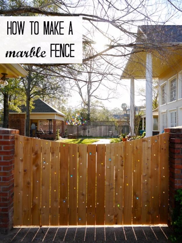 Marble fence, a cedar fence with colored glass marbles set into drilled holes between brick posts in a sunny backyard