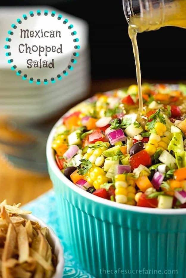 Turquoise bowl of Mexican chopped salad with corn, sweet peppers, red onion and zucchini, dressing poured over