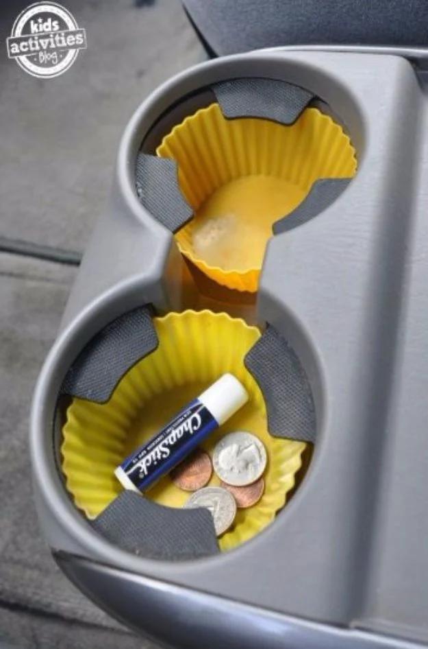 Silicone cupcake liners used as cup holder liners in a car, holding a lip balm and loose coins in yellow cups