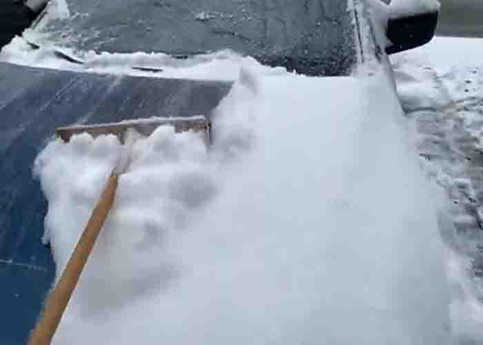 Cleaning snow off the car using a broom