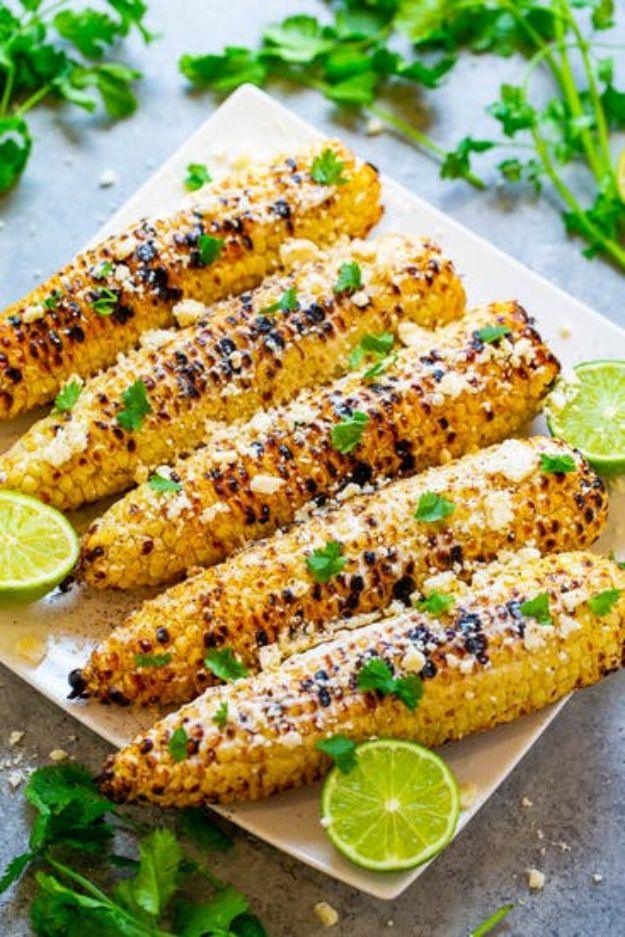 Grilled Mexican corn elote, charred cobs coated in crema and cotija with chili powder and lime wedges