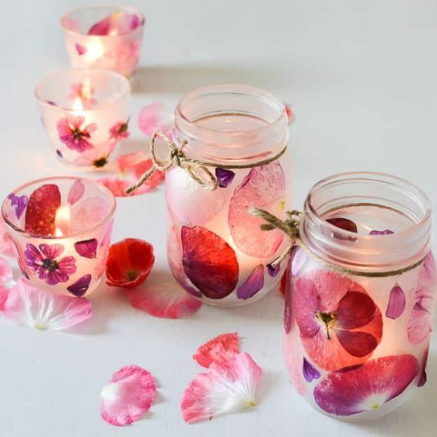 Glass jars and votives covered in pressed pink and purple flower petals, lit from inside, with loose petals scattered