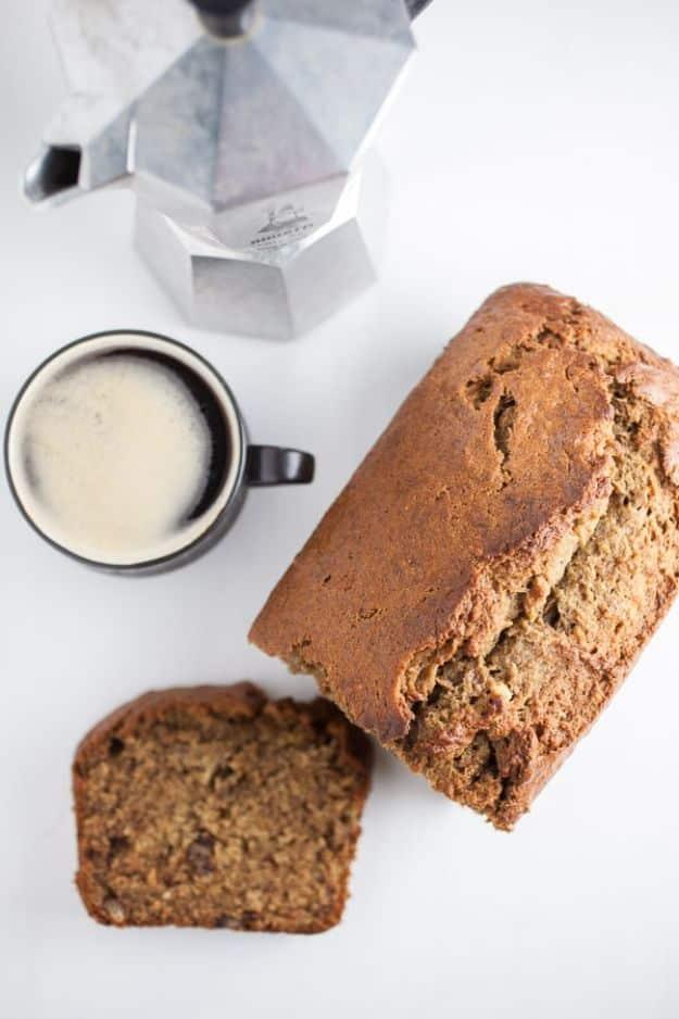 Coffee banana bread loaf with one slice cut, a small cup of espresso with crema and a moka pot behind it