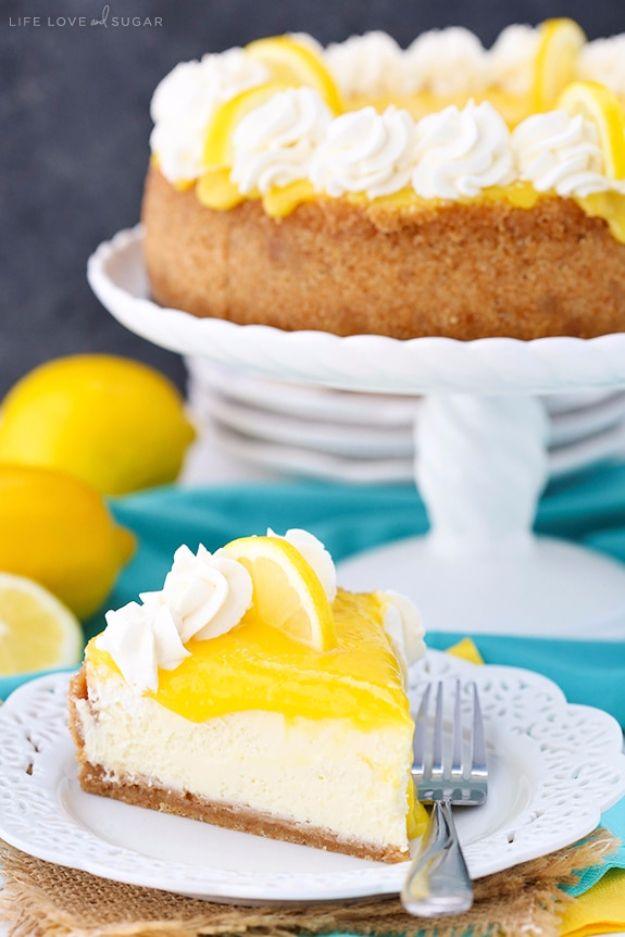 Lemon cheesecake topped with glossy yellow lemon curd and whipped cream rosettes beside whole fresh lemons