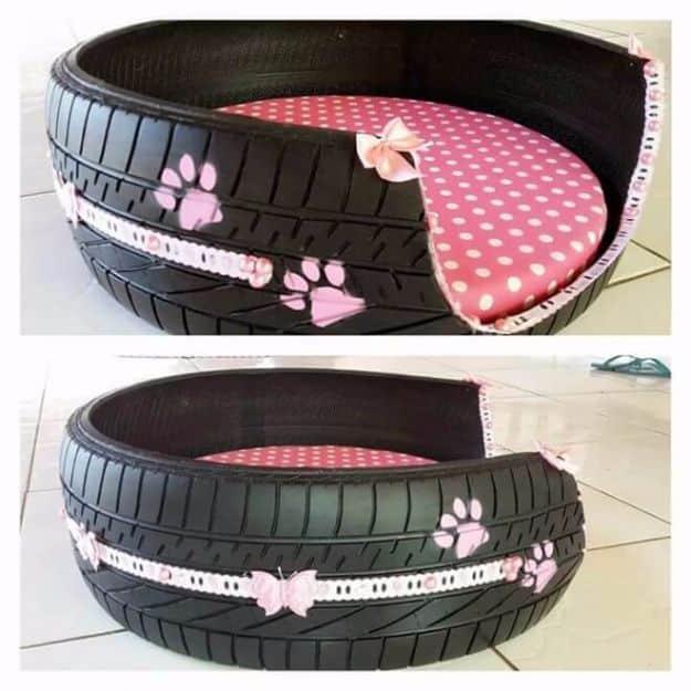 Old tire dog bed with a section cut away, a pink polka dot cushion inside and pale paw prints on the tread