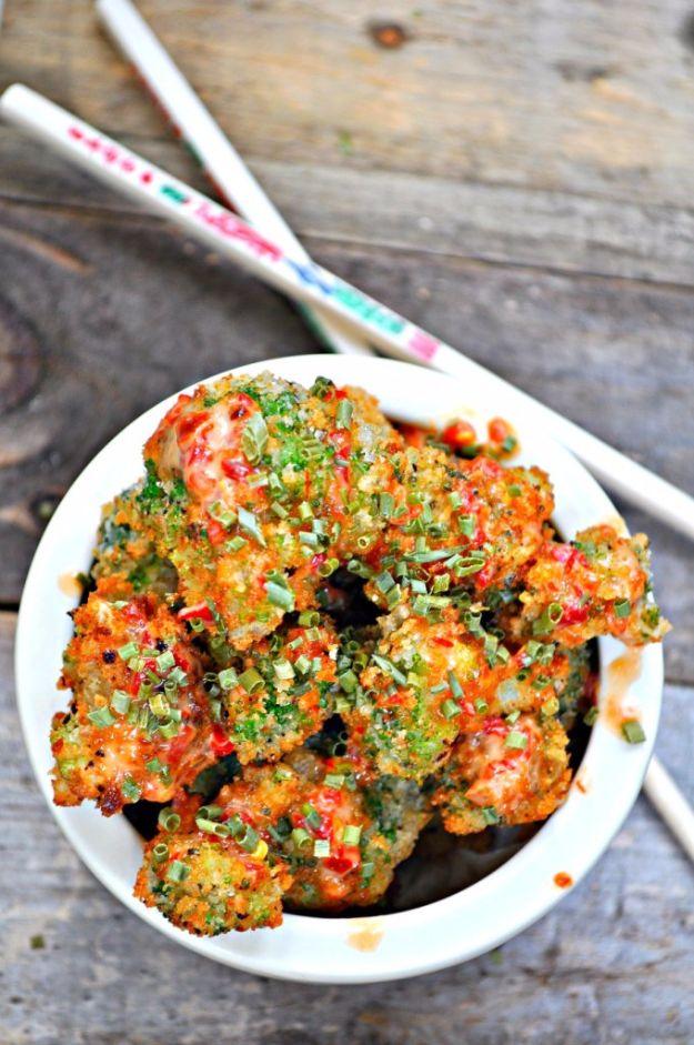 Vegan bang bang broccoli florets in a crisp panko crust, coated in orange chili sauce and scattered with chopped chives