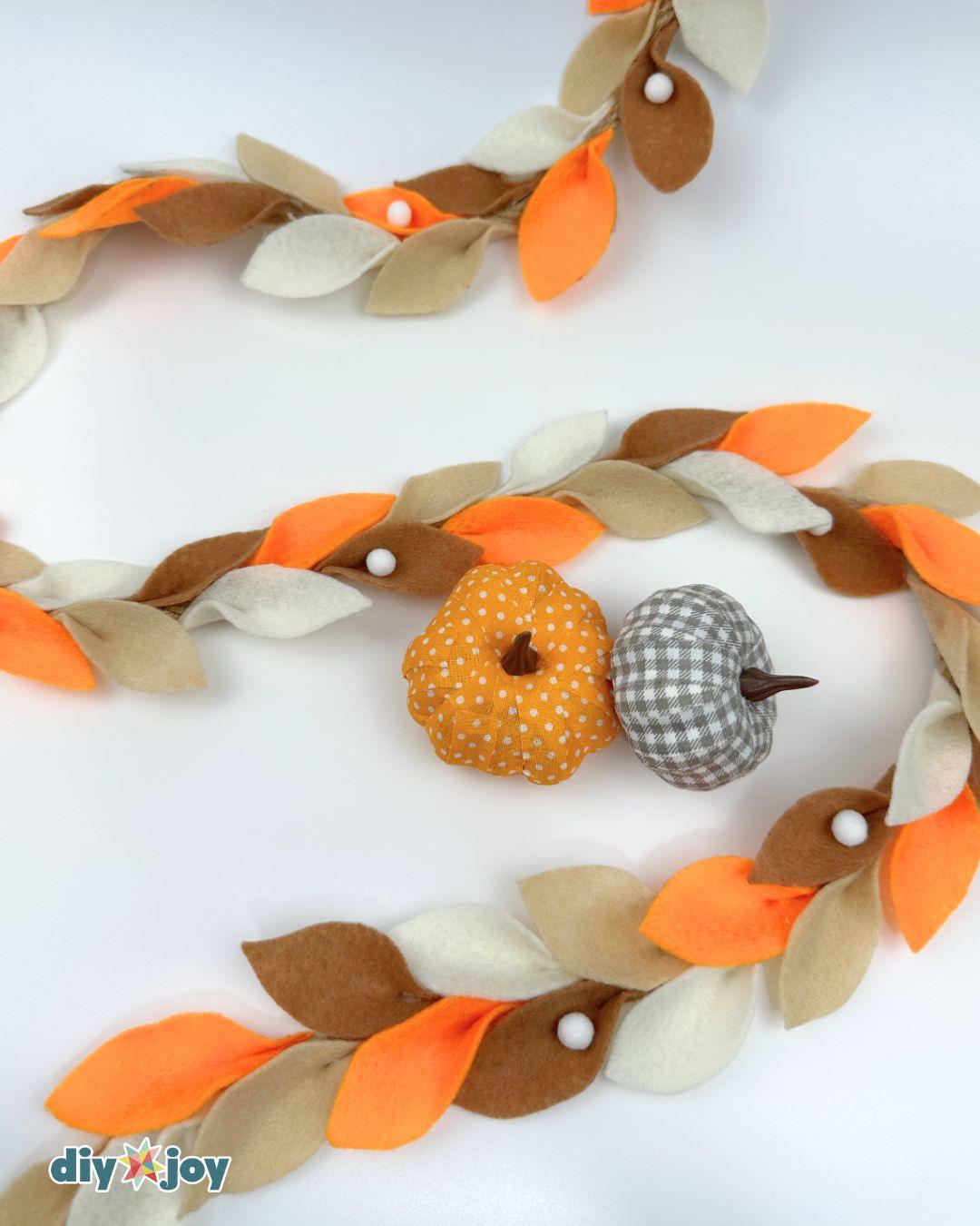 DIY fall leaf garland made with felt leaves in orange, cream, tan, and brown for a fireplace mantel.